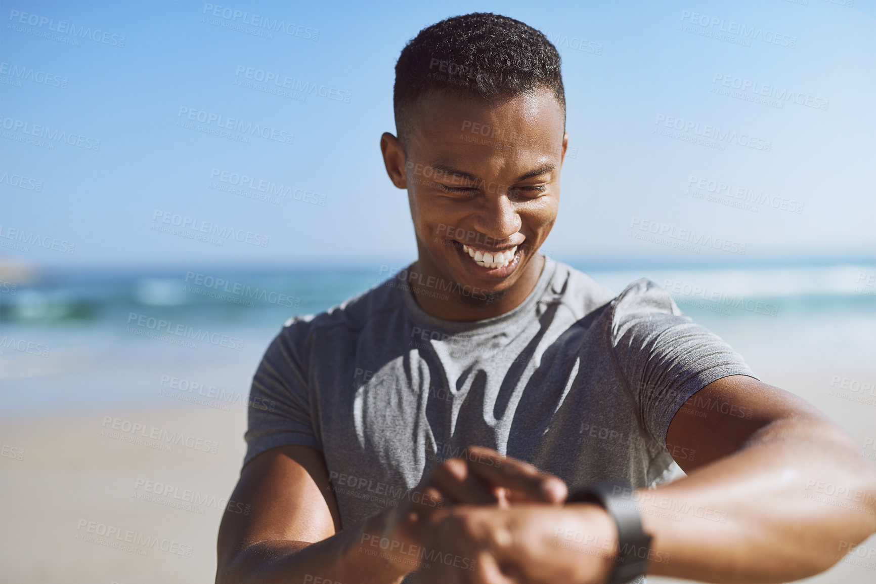 Buy stock photo Shot of a sporty young man checking his smartwatch while exercising outdoors