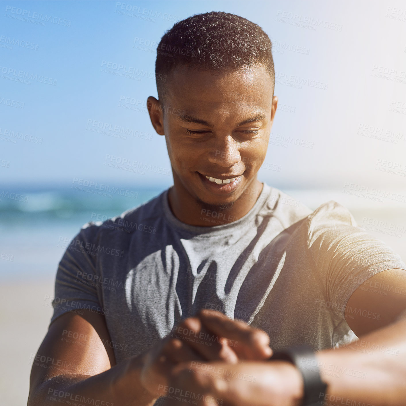 Buy stock photo Shot of a sporty young man checking his smartwatch while exercising outdoors