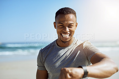 Buy stock photo Portrait of a sporty young man checking his smartwatch while exercising outdoors