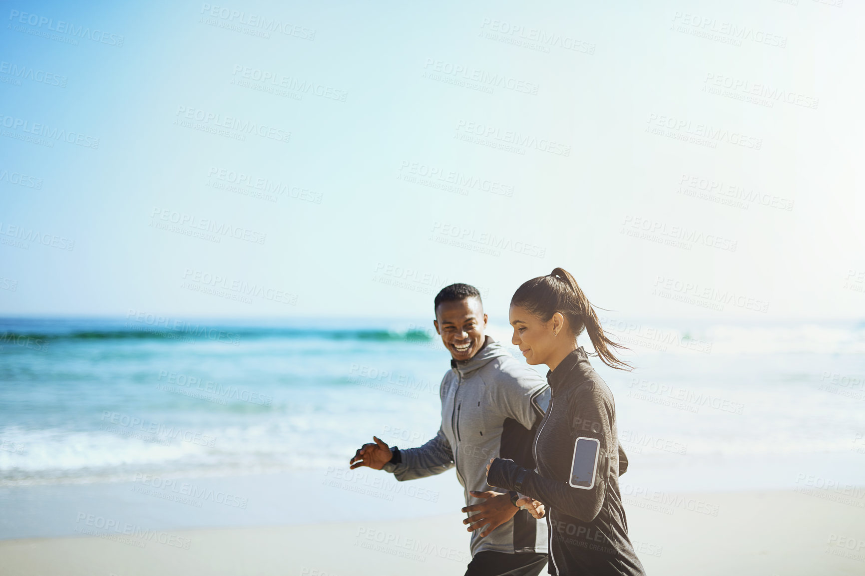 Buy stock photo Shot of a sporty young couple out for a run along the beach