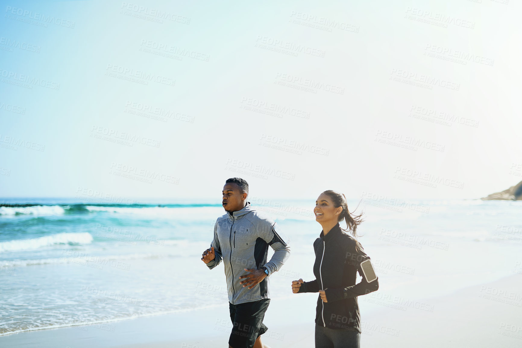 Buy stock photo Shot of a sporty young couple out for a run along the beach
