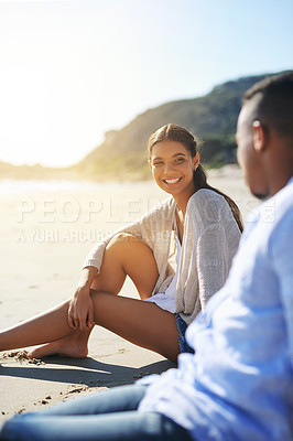 Buy stock photo Shot of a young couple relaxing together at the beach