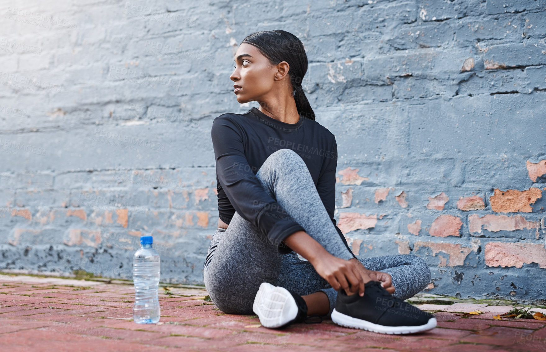 Buy stock photo Shot of a young woman tying her shoelaces before a workout session