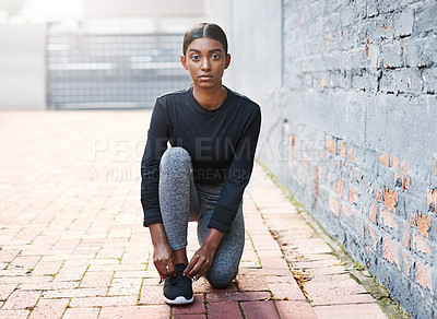 Buy stock photo Shot of a young woman tying her shoelaces before a workout session