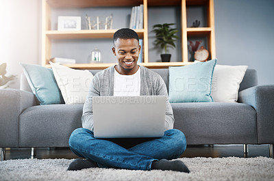 Buy stock photo Shot of a happy young man using a laptop while relaxing at home