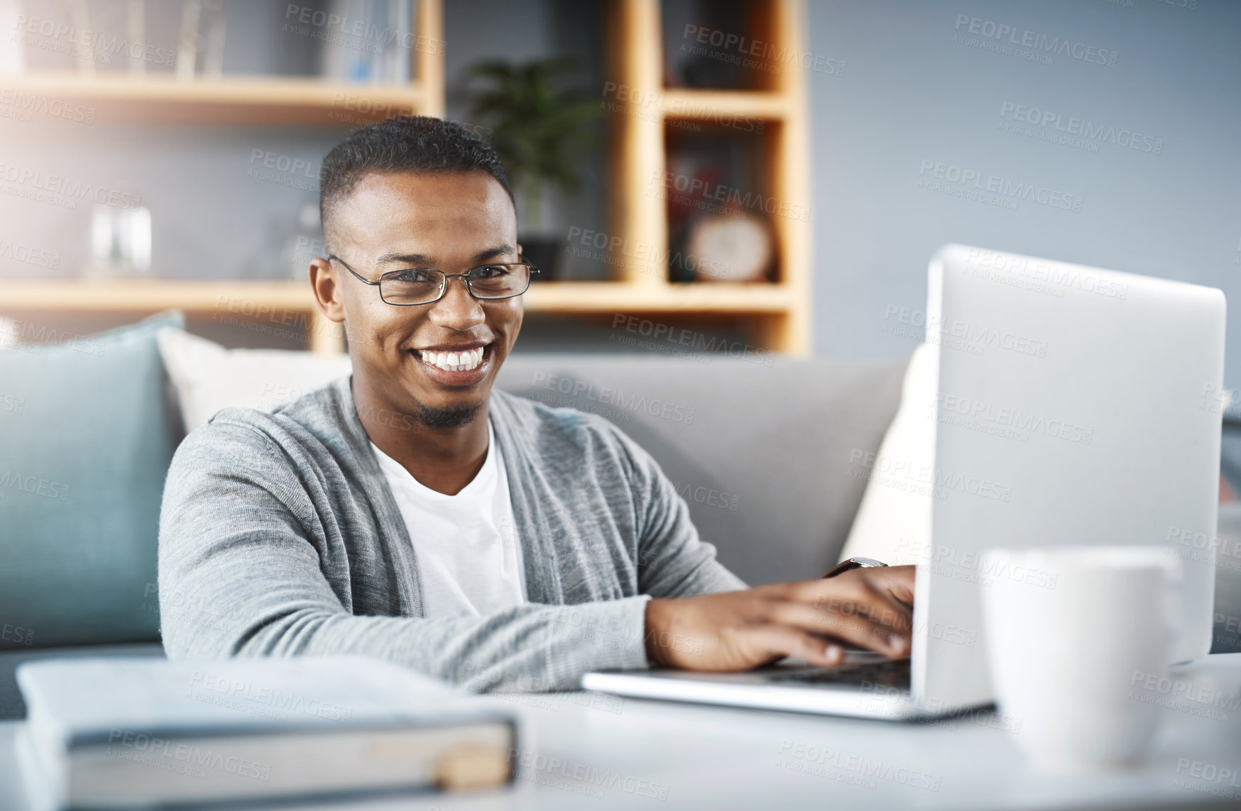Buy stock photo Portrait of a happy young man using a laptop while relaxing at home