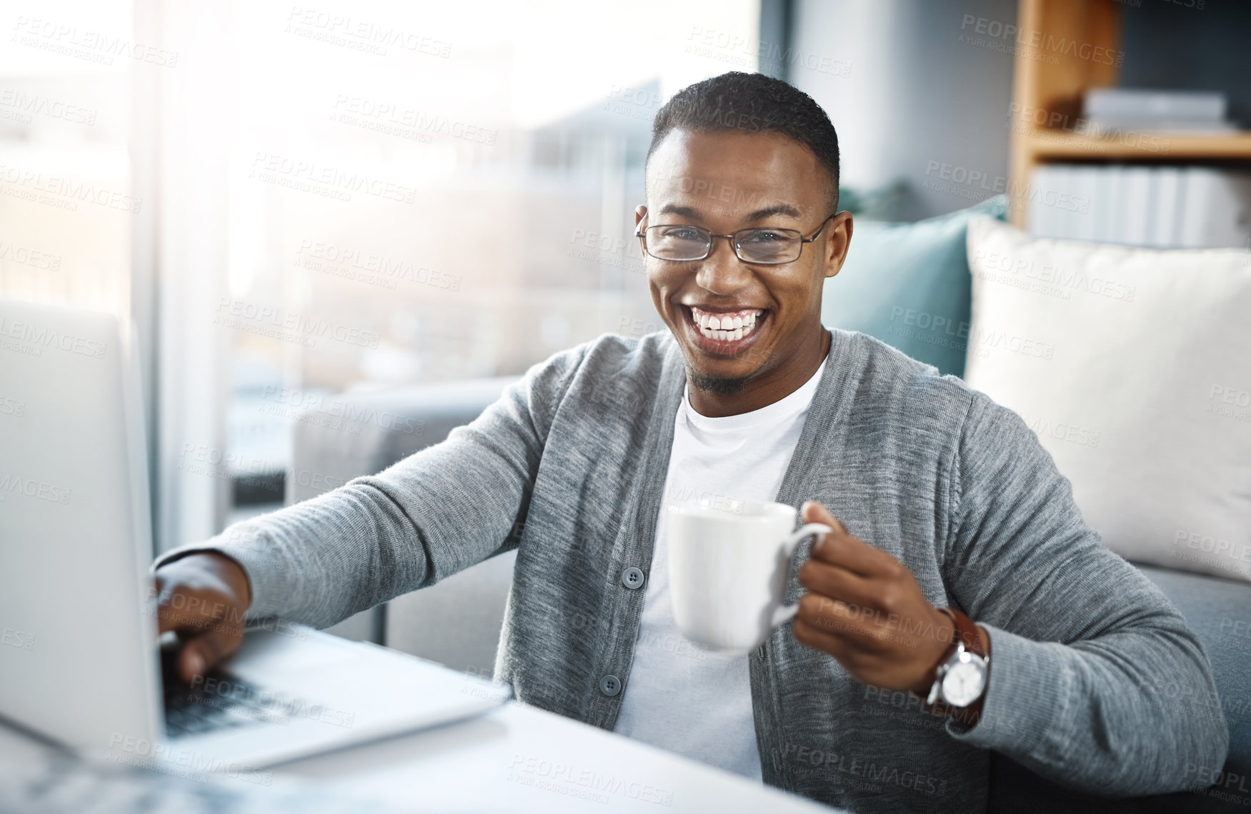 Buy stock photo Portrait of a young man having coffee and using a laptop while relaxing at home