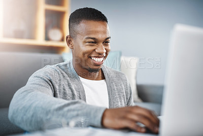 Buy stock photo Shot of a happy young man using a laptop while relaxing at home