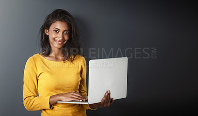Buy stock photo Studio portrait of an attractive young woman using a laptop against a gray background