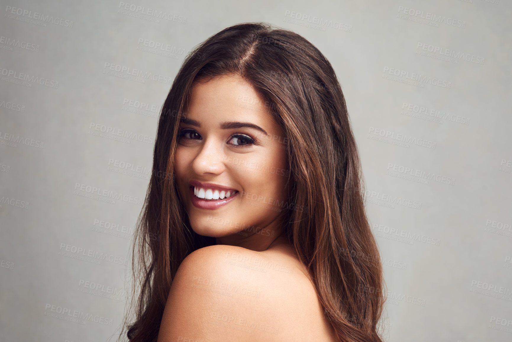 Buy stock photo Happy woman, portrait and skincare with hair for beauty, makeup or cosmetics on a gray studio background. Face of young female person, brunette or model with smile for haircare salon, glow or shine