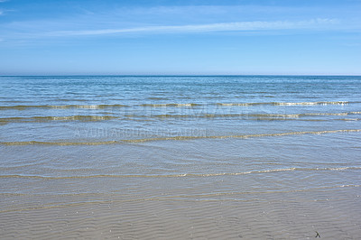 Buy stock photo Small ocean waves on the shore against a clear blue sky with copy space. Landscape of the wide open sea or beach with calm water on a bright sunny day. Sea surface with ripples on the horizon