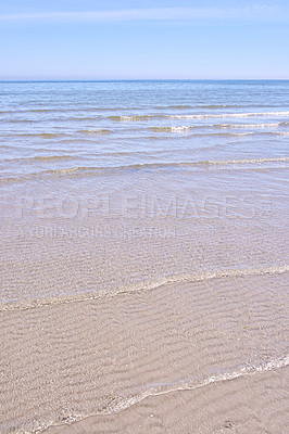 Buy stock photo Beautiful beach seascape and horizon under a clear blue sky, copy space. Calm and tranquil ocean scenery with the sea during a low tide on a sunny day. A quiet coastal holiday by the ocean shore