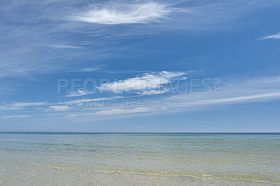 Buy stock photo Copyspace at the beach with a cloudy blue sky background above the horizon. Calm ocean waves across an empty sea along the coast. Peaceful and tranquil landscape for a relaxing and zen summer getaway