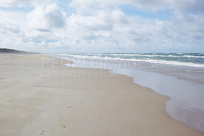 Buy stock photo An empty beach on a cloudy morning with copyspace.  Ocean waves washing onto a sandy shore, calm, peaceful day in relaxing zen environment. Copy space at sea with clouds in the sky in the background