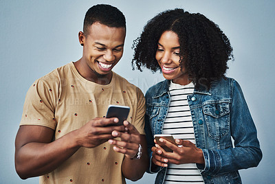 Buy stock photo Studio shot of a young man and woman using a mobile phone together against a gray background