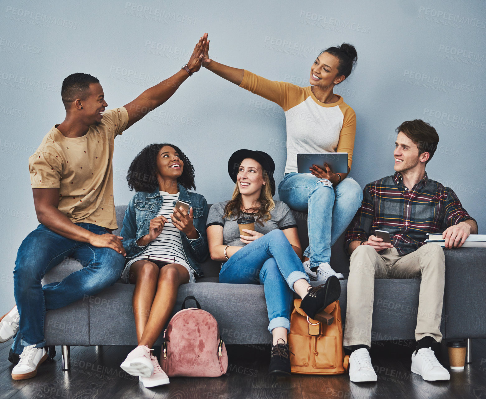 Buy stock photo Studio shot of a young man and woman giving each other a high five while hanging out with their friends