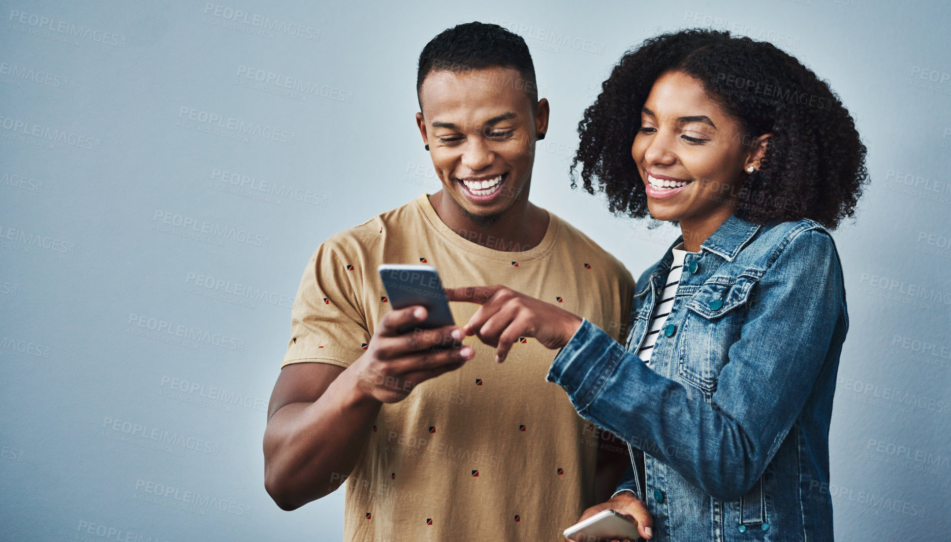 Buy stock photo Studio shot of a young man and woman using a mobile phone together against a gray background