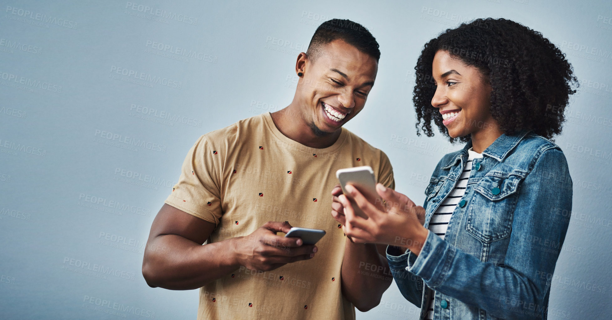 Buy stock photo Studio shot of a young man and woman using a mobile phone together against a gray background