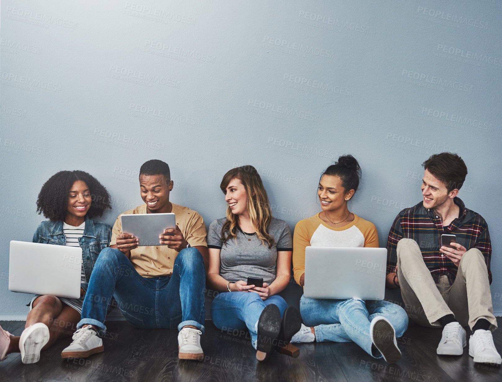 Buy stock photo Studio shot of a group of young people using wireless technology against a gray background