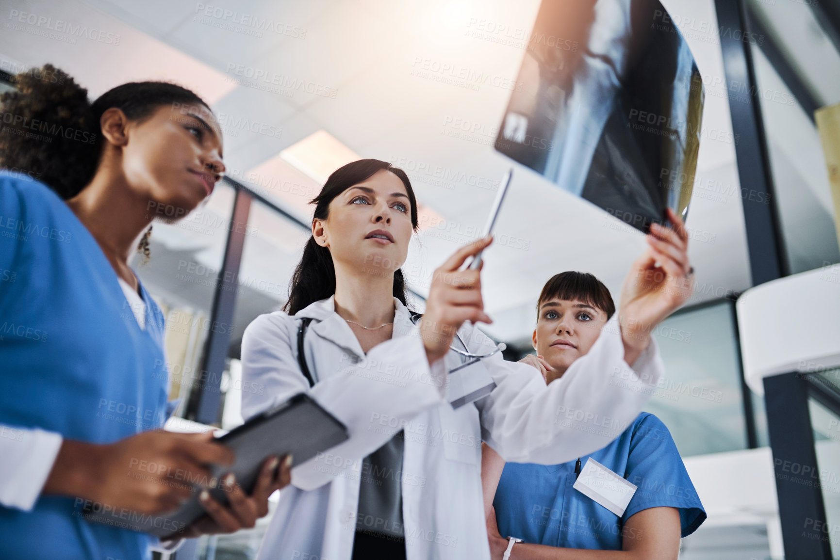 Buy stock photo Shot of a group of doctors discussing the results of an X-ray in a hospital