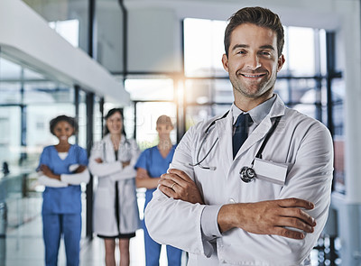 Buy stock photo Portrait of a confident young doctor working in a hospital with his colleagues in the background