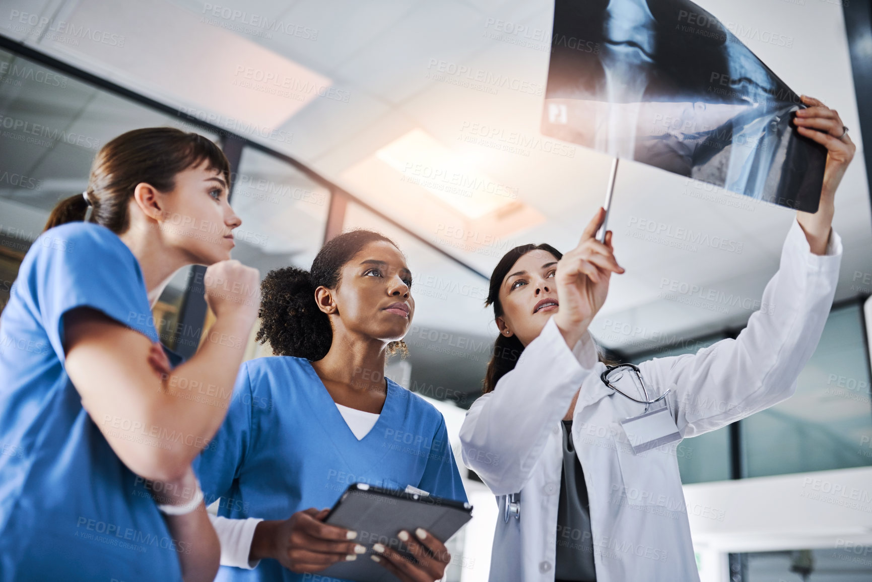 Buy stock photo Shot of a group of doctors discussing the results of an X-ray in a hospital