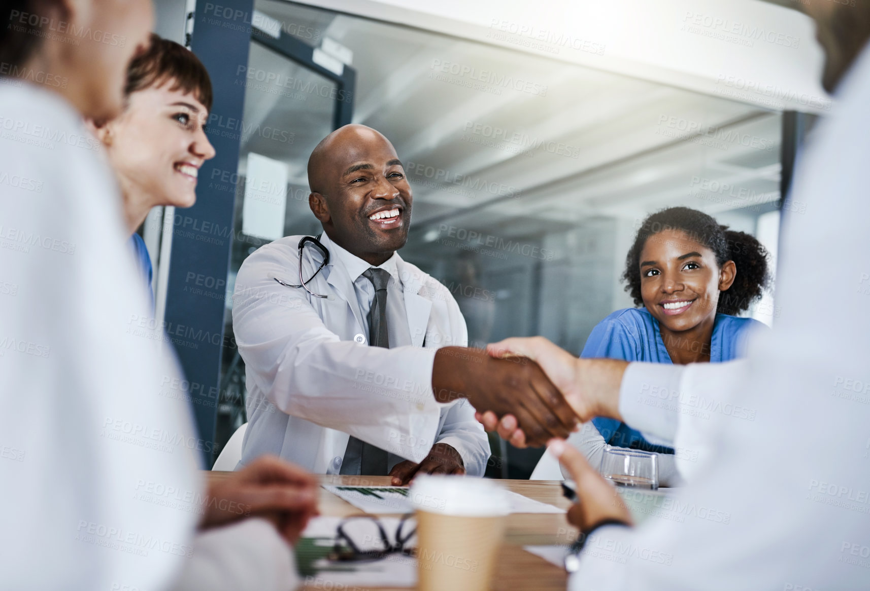 Buy stock photo Shot of doctors shaking hands during a meeting in a hospital