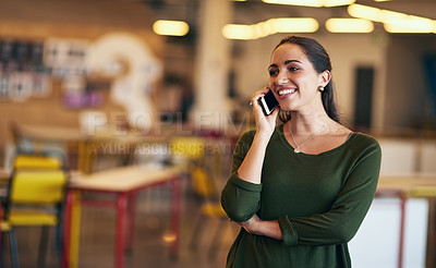 Buy stock photo Shot of a confident young woman talking on her cellphone while standing in an modern office