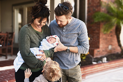 Buy stock photo Shot of a young cheerful family standing together outside at home during the day