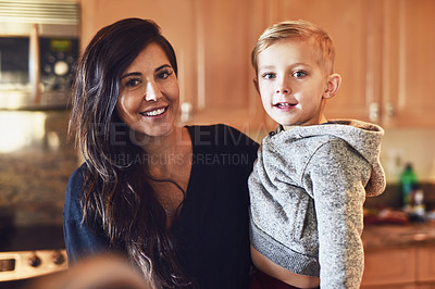 Buy stock photo Portrait of a cheerful young woman and her little boy standing in the kitchen together at home during the day
