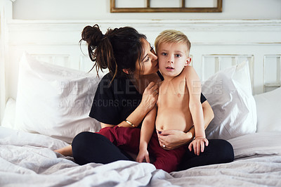 Buy stock photo Shot of a cheerful little boy and his mother hanging out on the bed at home while relaxing during the day