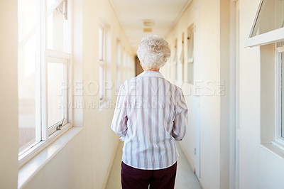 Buy stock photo Rearview shot of a senior woman walking down a corridor in a retirement home