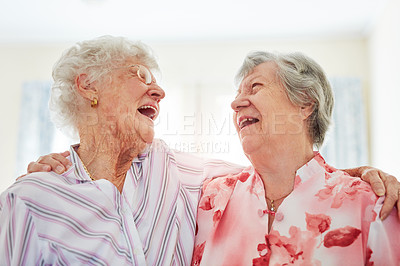 Buy stock photo Shot of two happy elderly women embracing each other at home