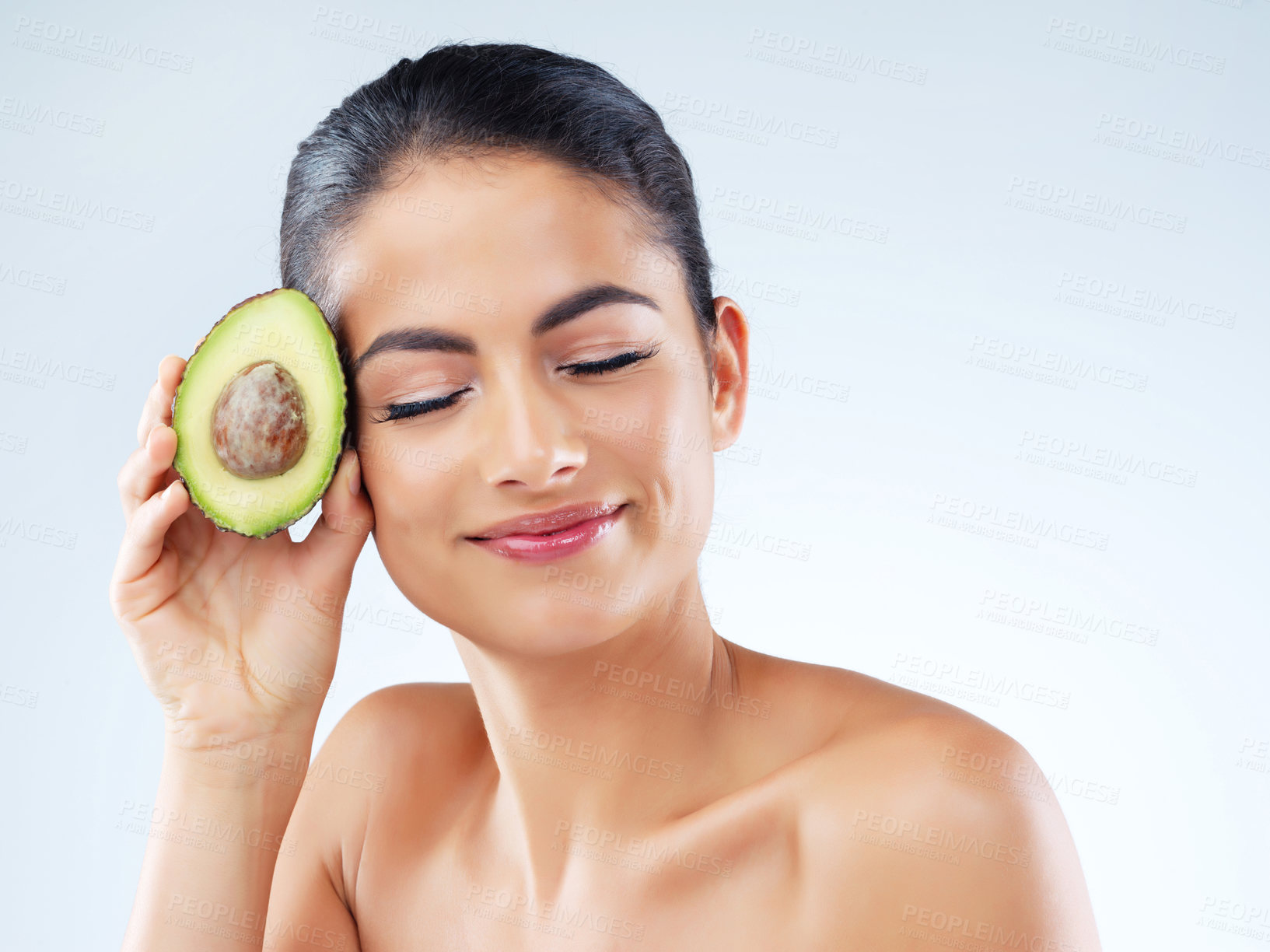 Buy stock photo Studio portrait of an attractive young woman holding an avocado against a gray background