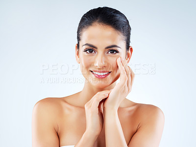 Buy stock photo Studio portrait of an attractive young woman feeling her skin against a gray background