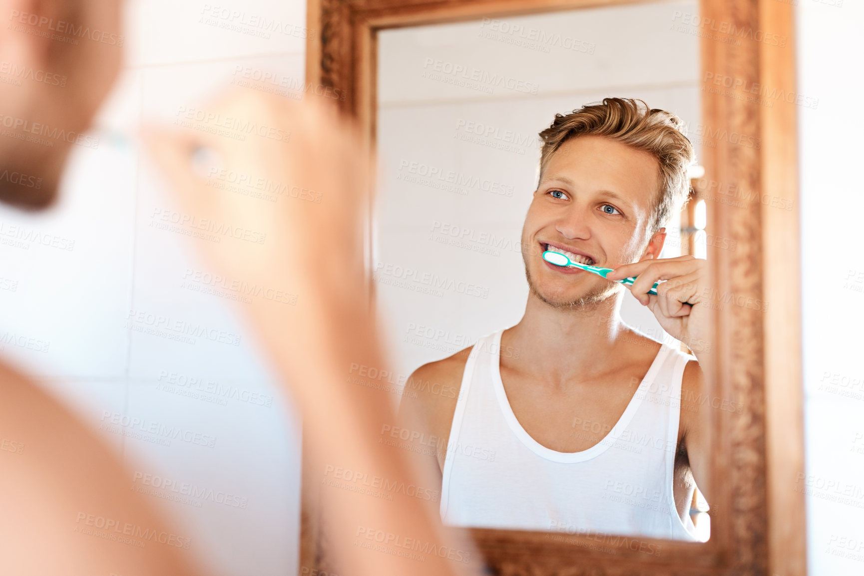 Buy stock photo Shot of a young man brushing his teeth at home