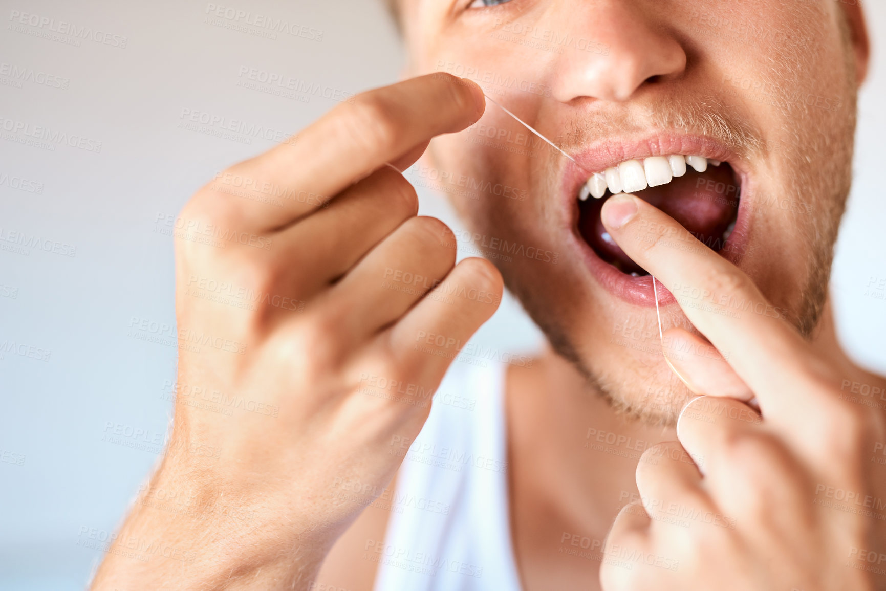 Buy stock photo Closeup shot of a young man flossing his teeth at home