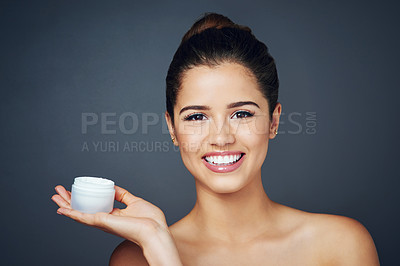 Buy stock photo Studio shot of a beautiful young woman with flawless skin posing with moisturizer against a blue background