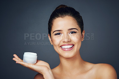 Buy stock photo Studio shot of a beautiful young woman with flawless skin posing with moisturizer against a blue background
