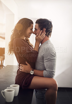 Buy stock photo Shot of an affectionate young couple hugging in the kitchen at home