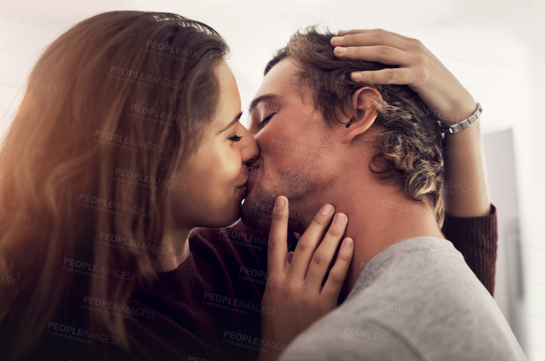 Buy stock photo Face, couple and kiss for love, care and intimate moment for anniversary, honeymoon and bonding together at home. Happy young man, woman and kissing with passion, romance and lovers in relationship