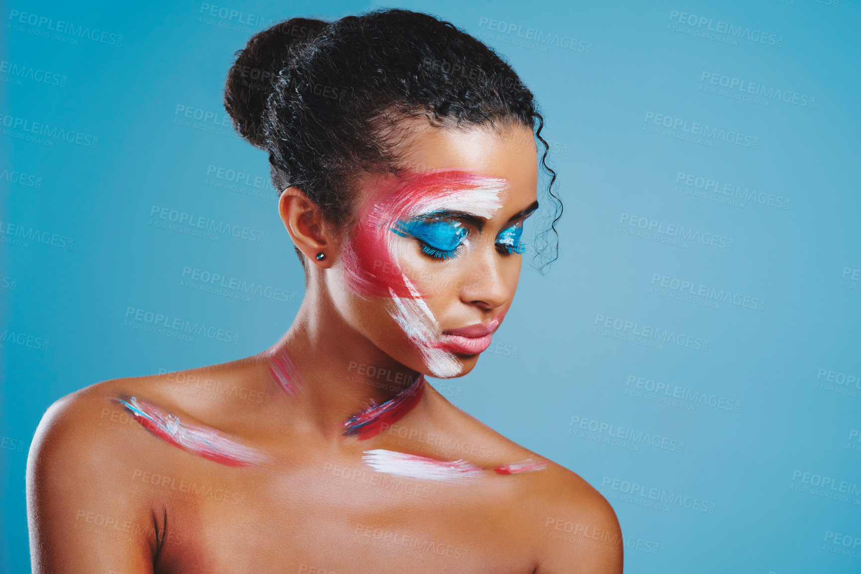 Buy stock photo Studio shot of a beautiful young woman covered in face paint posing against a blue background