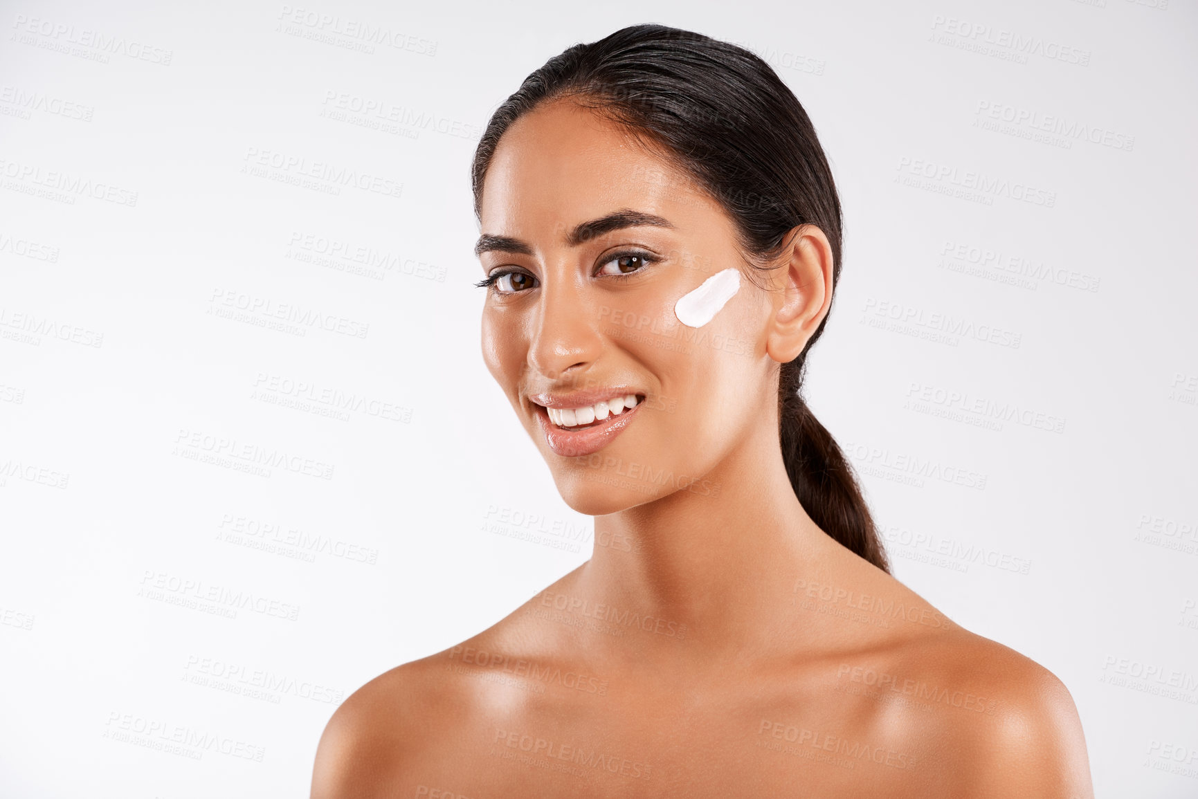 Buy stock photo Studio portrait of a beautiful young woman posing with lotion on her face against a gray background