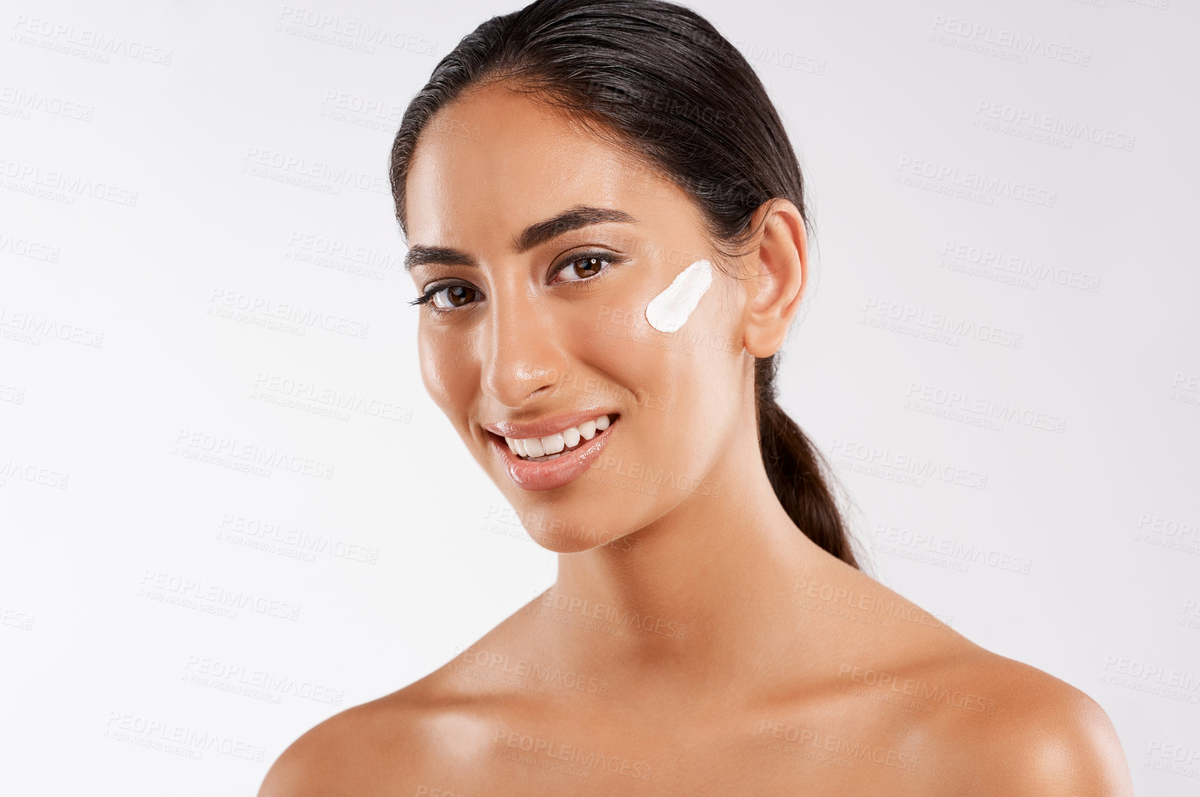 Buy stock photo Studio portrait of a beautiful young woman posing with lotion on her face against a gray background