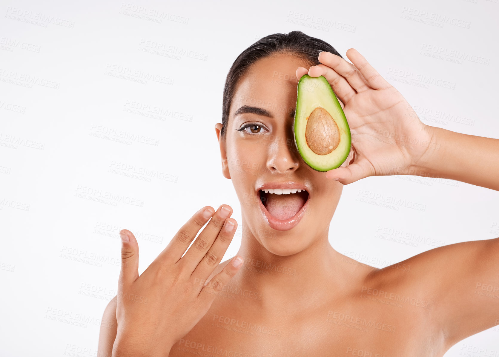 Buy stock photo Studio portrait of a beautiful young woman holding half an avocado against a gray background