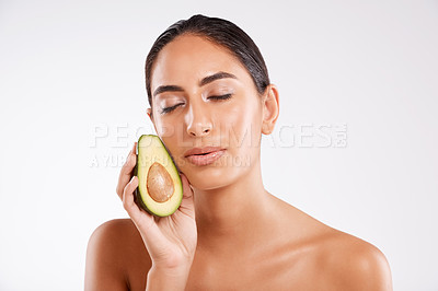 Buy stock photo Studio shot of a beautiful young woman holding half an avocado against a gray background