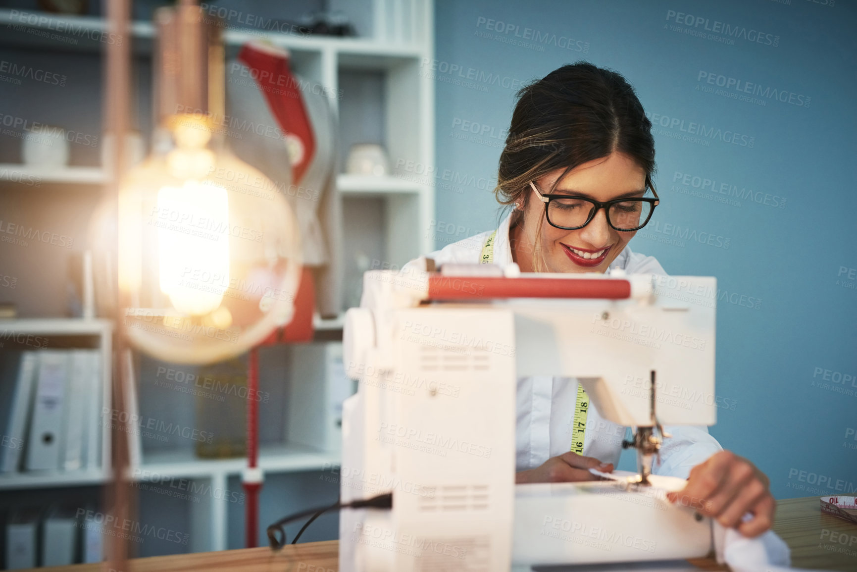 Buy stock photo Cropped shot of an attractive young fashion designer using a sewing machine in her design workshop