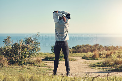 Buy stock photo Rearview shot of an unrecognizable young man stretching before exercising outdoors