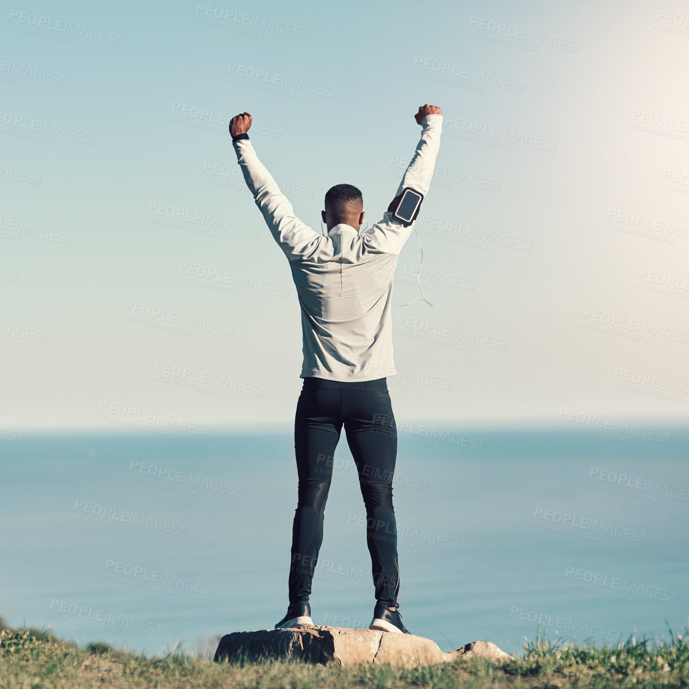 Buy stock photo Rearview shot of an unrecognizable young man standing with his hands raised while exercising outdoors