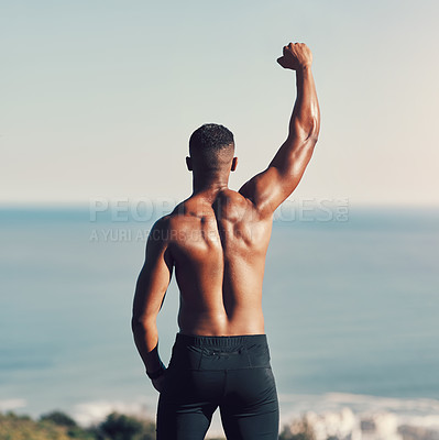 Buy stock photo Rearview shot of an unrecognizable young man standing with his hand raised while exercising outdoors